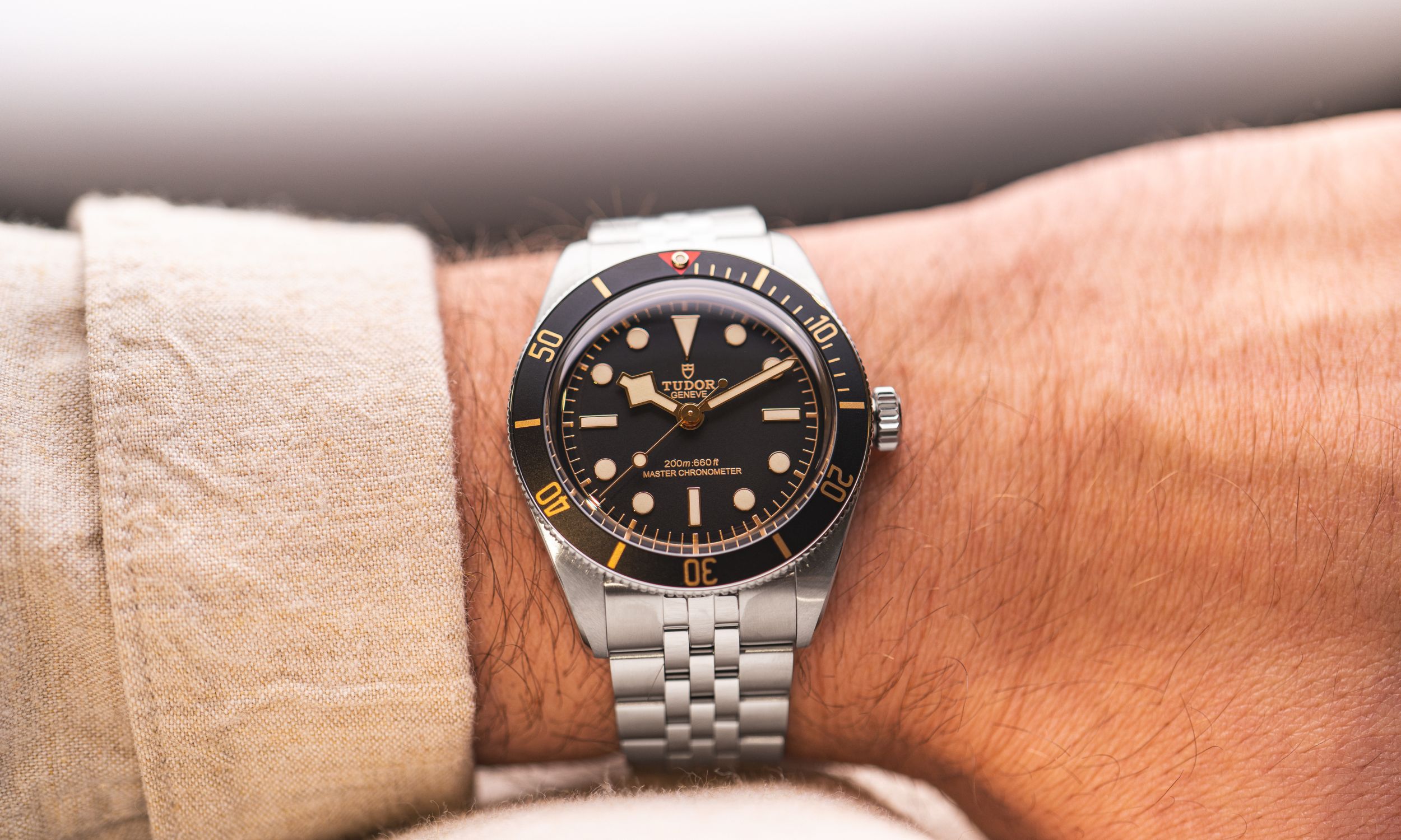 Wristshot der neuen TUDOR Black Bay 58 am Stahlarmband mit beiger Hemdmanschette