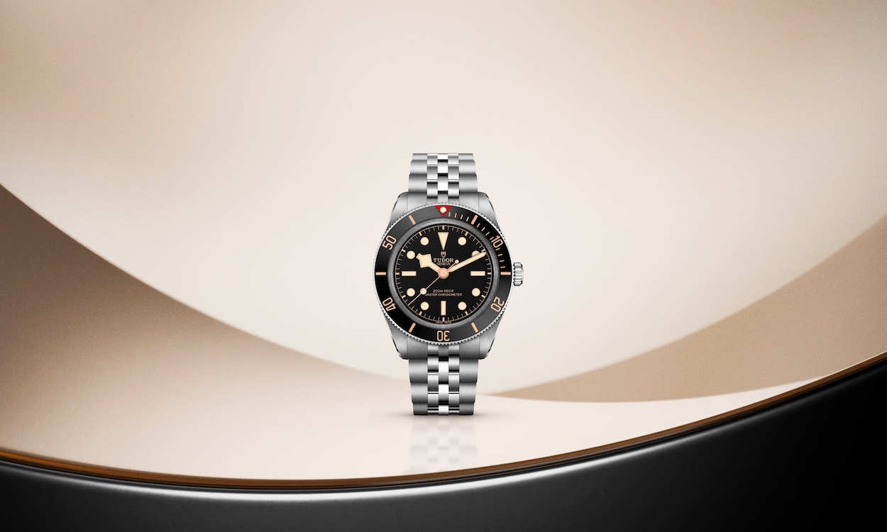 TUDOR Black Bay 58 am fünfreihigen Edelstahlband in Nahaufnahme vor goldenem Hintergrund