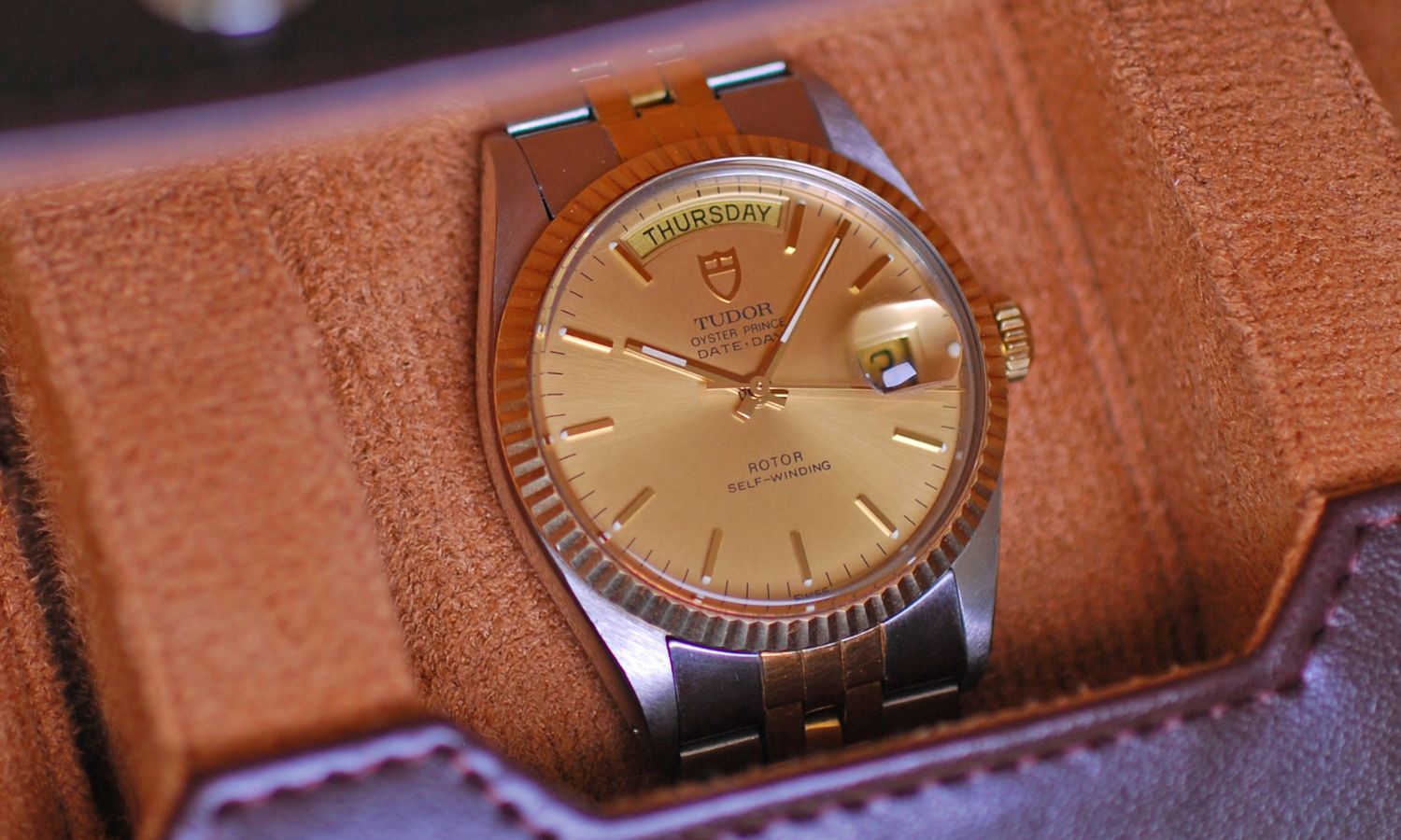 TUDOR Oyster Prince Date-Day Referenz 94613 mit goldenem Zifferblatt am Edelstahlarmband in einer Uhrenrolle abgebildet