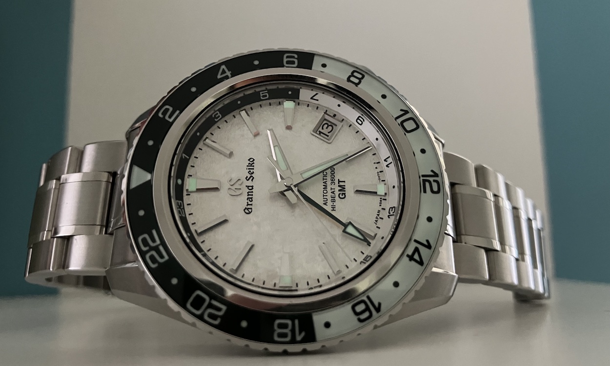 Grand Seiko SBGJ277 liegend auf weißem Untergrund vor weiß blauem Hintergrund