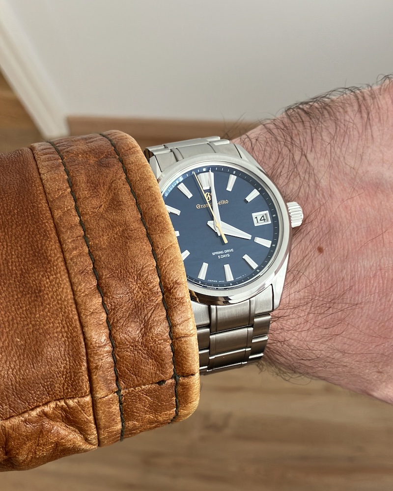 Grand Seiko SLGA007 am Handgelenk eines Mannes mit brauner Lederjacke